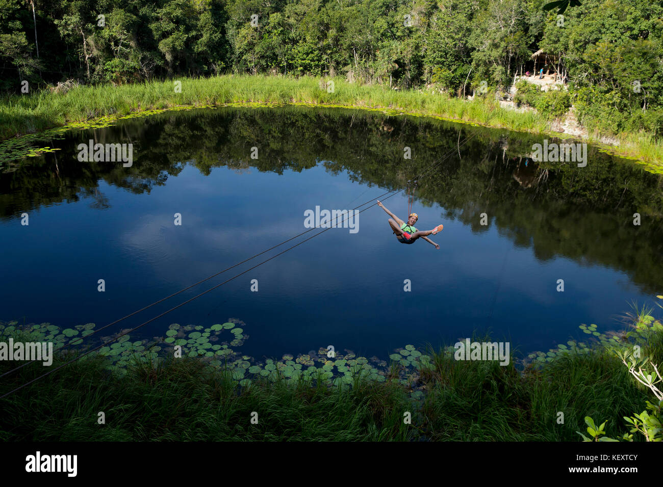 Tourist enjoying zip line over lagoon and cenotes of village near Cob