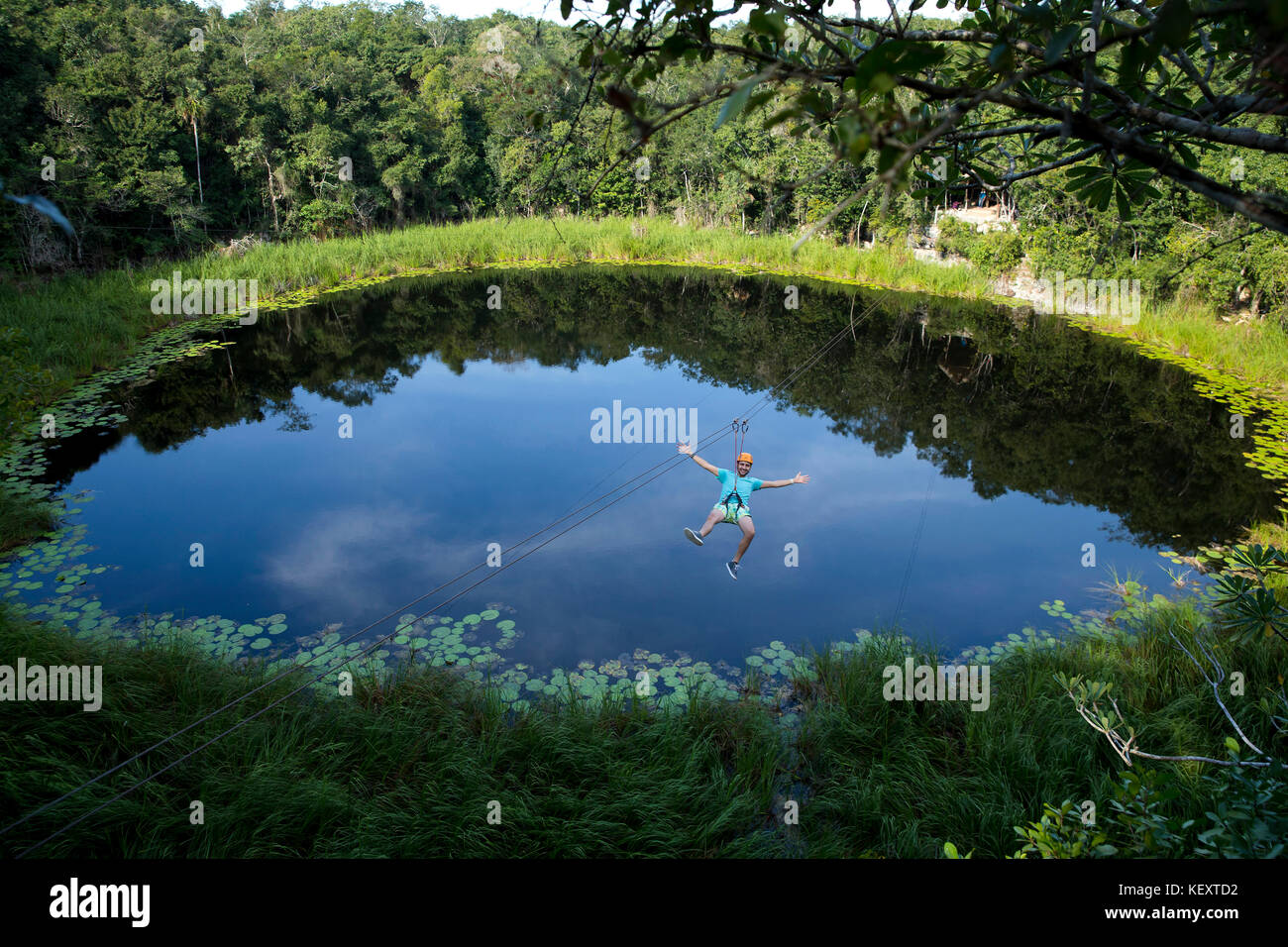 Tourist enjoying zip line over lagoon and cenotes of village near Cob