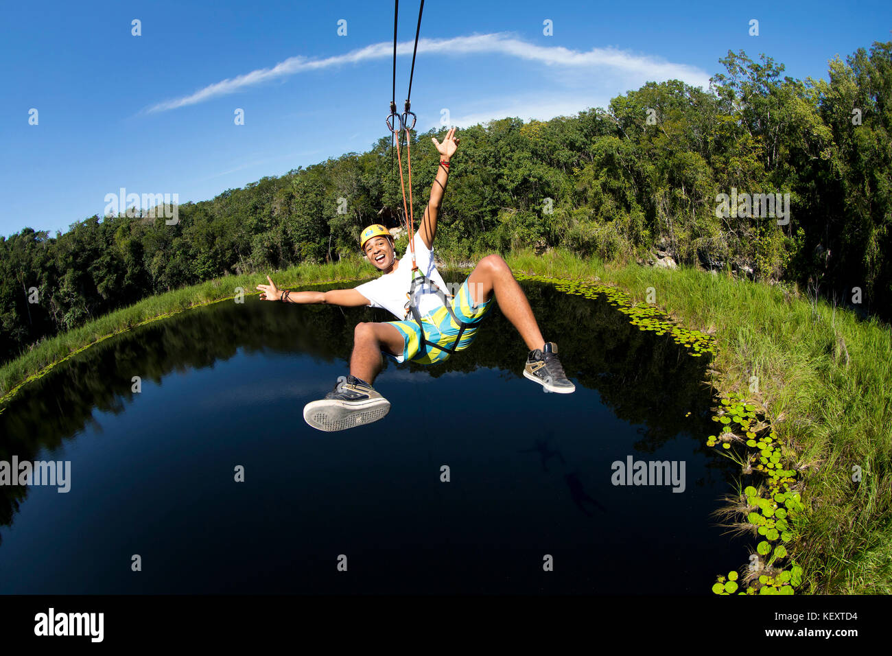 Tourist enjoying zip line over lagoon and cenotes of village near Cob