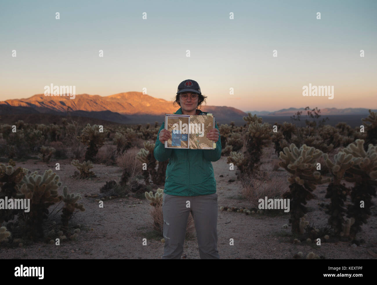 Portrait of woman standing in Chollah Cactus Garden and holding guidebook, California, USA Stock Photo