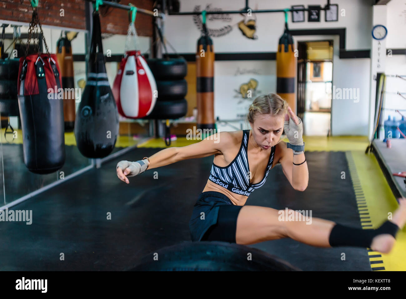 Photograph of young woman in gym kicking while practicing kickboxing, Seminyak, Bali, Indonesia Stock Photo