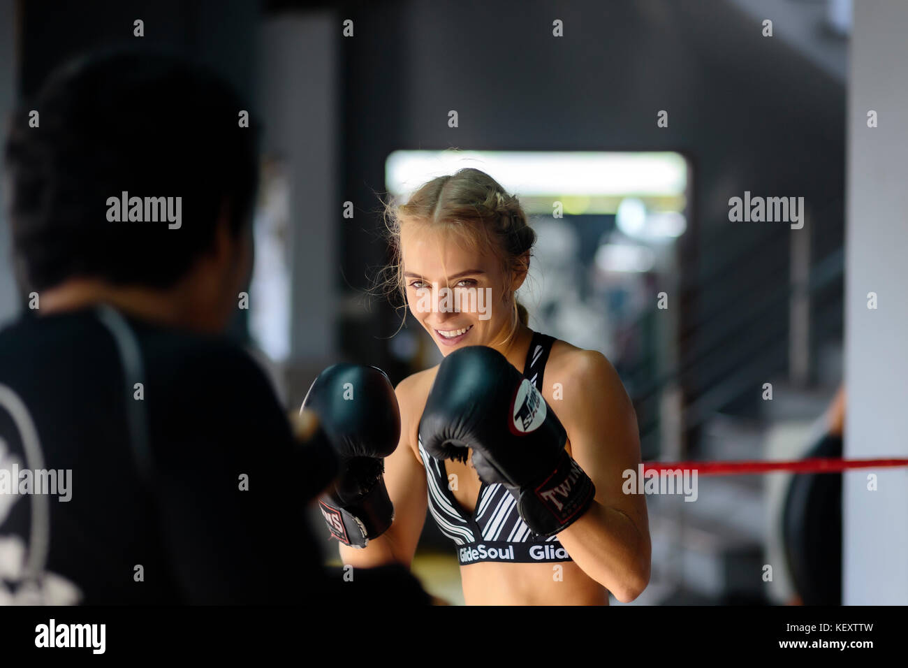Photograph of young female kickboxer in fighting stance in ring with coach, Seminyak, Bali, Indonesia Stock Photo