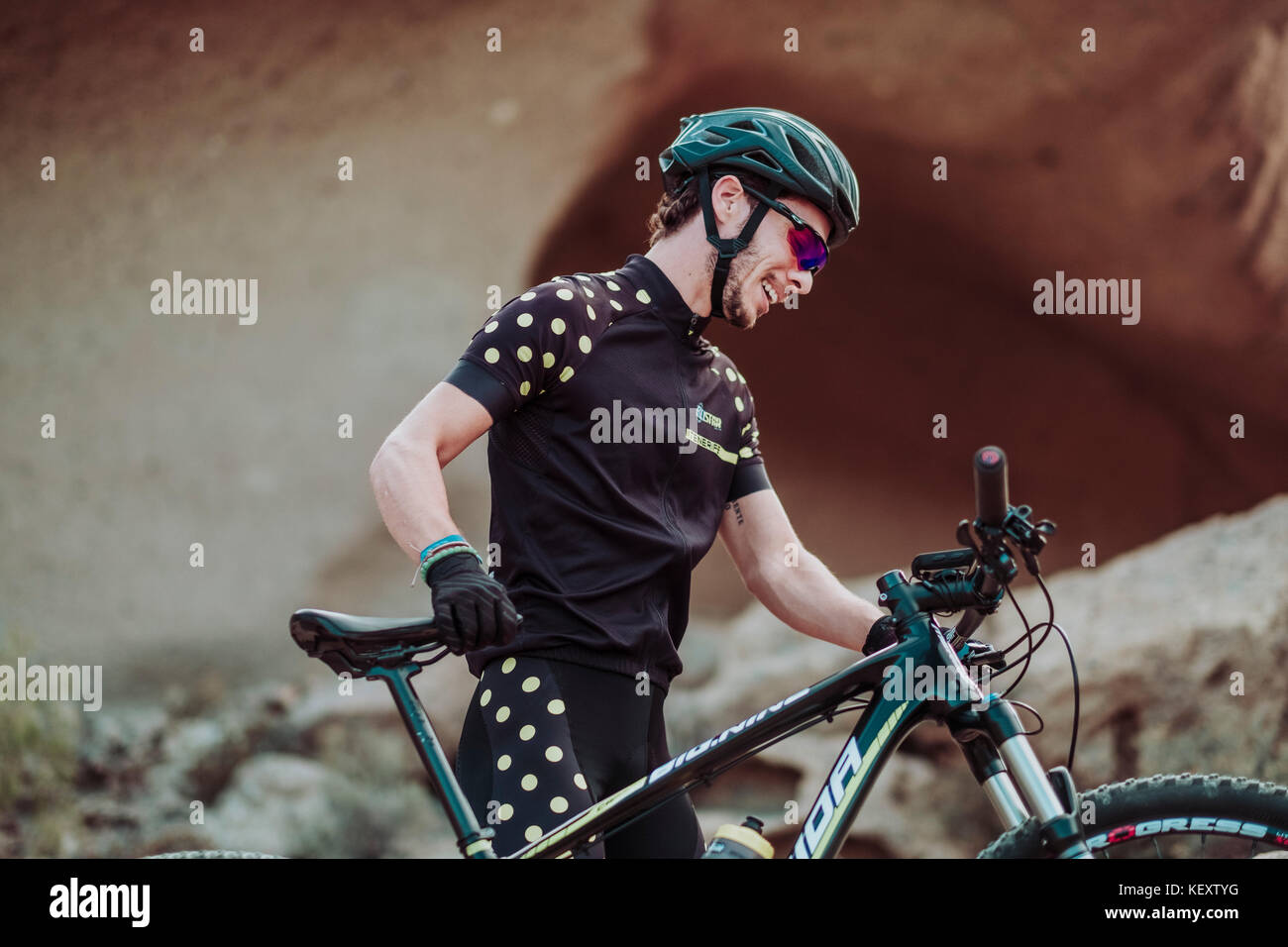 Man walking in desert with his mountain bike, Tenerife, Canary Islands, Spain Stock Photo