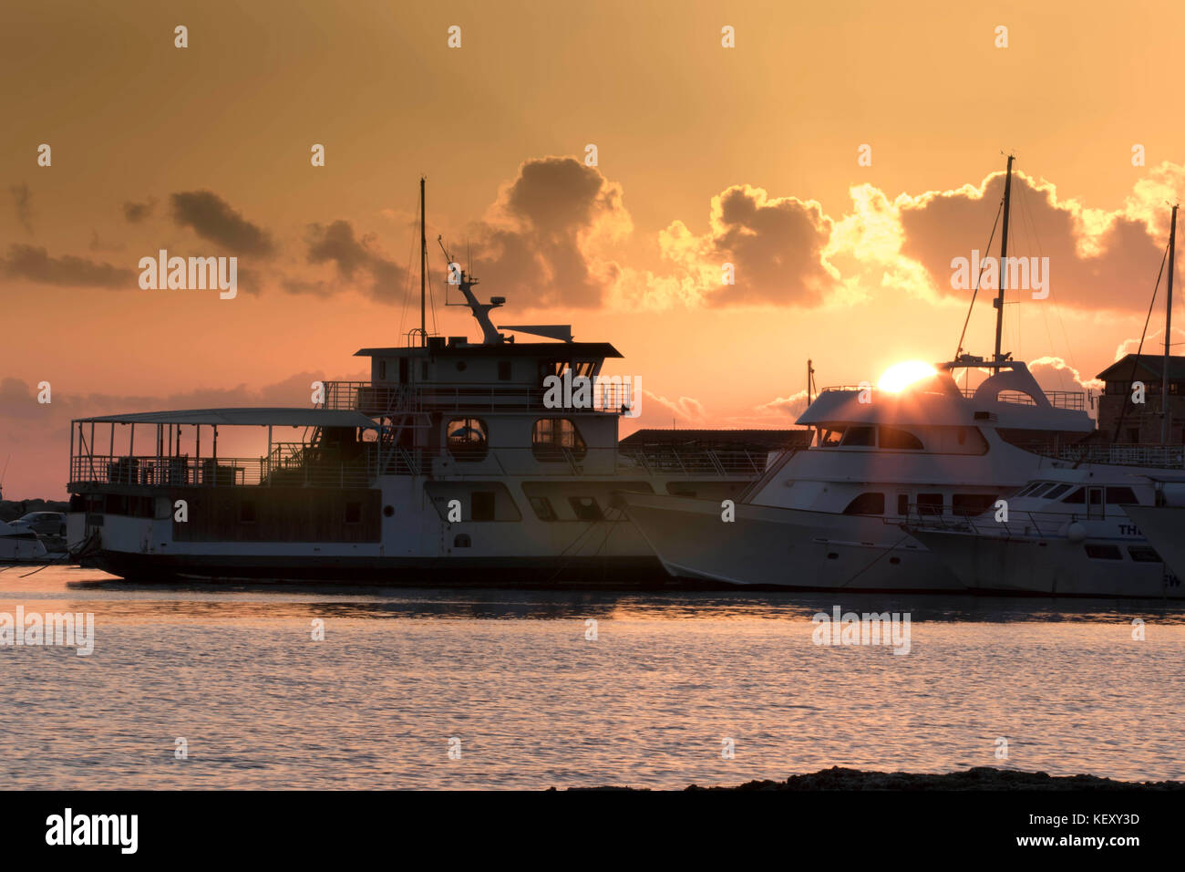 Pleasure boats in Paphos harbour with the setting sun on the mediterranean horizon, Paphos in cyprus, Europe. Stock Photo