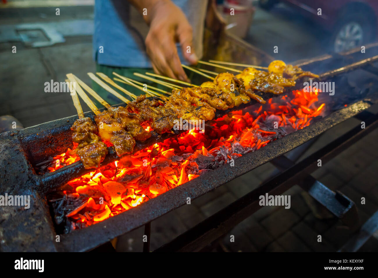 Street barbecue with meat skewers sizzling, very hot fire burning and