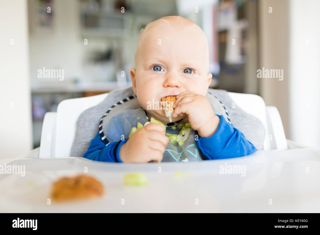 Baby boy eating bread and cucumber with BLW method, baby led weaning