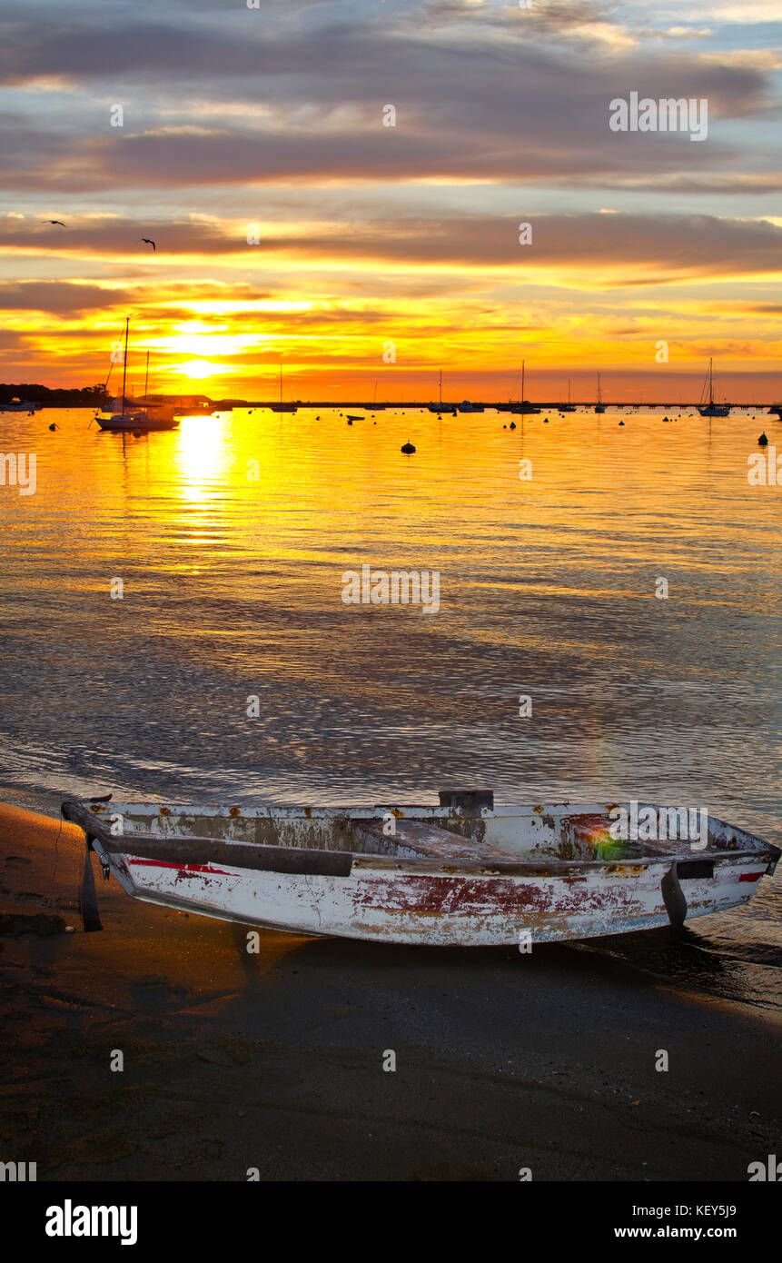 Small dingy on beach at sunset Stock Photo