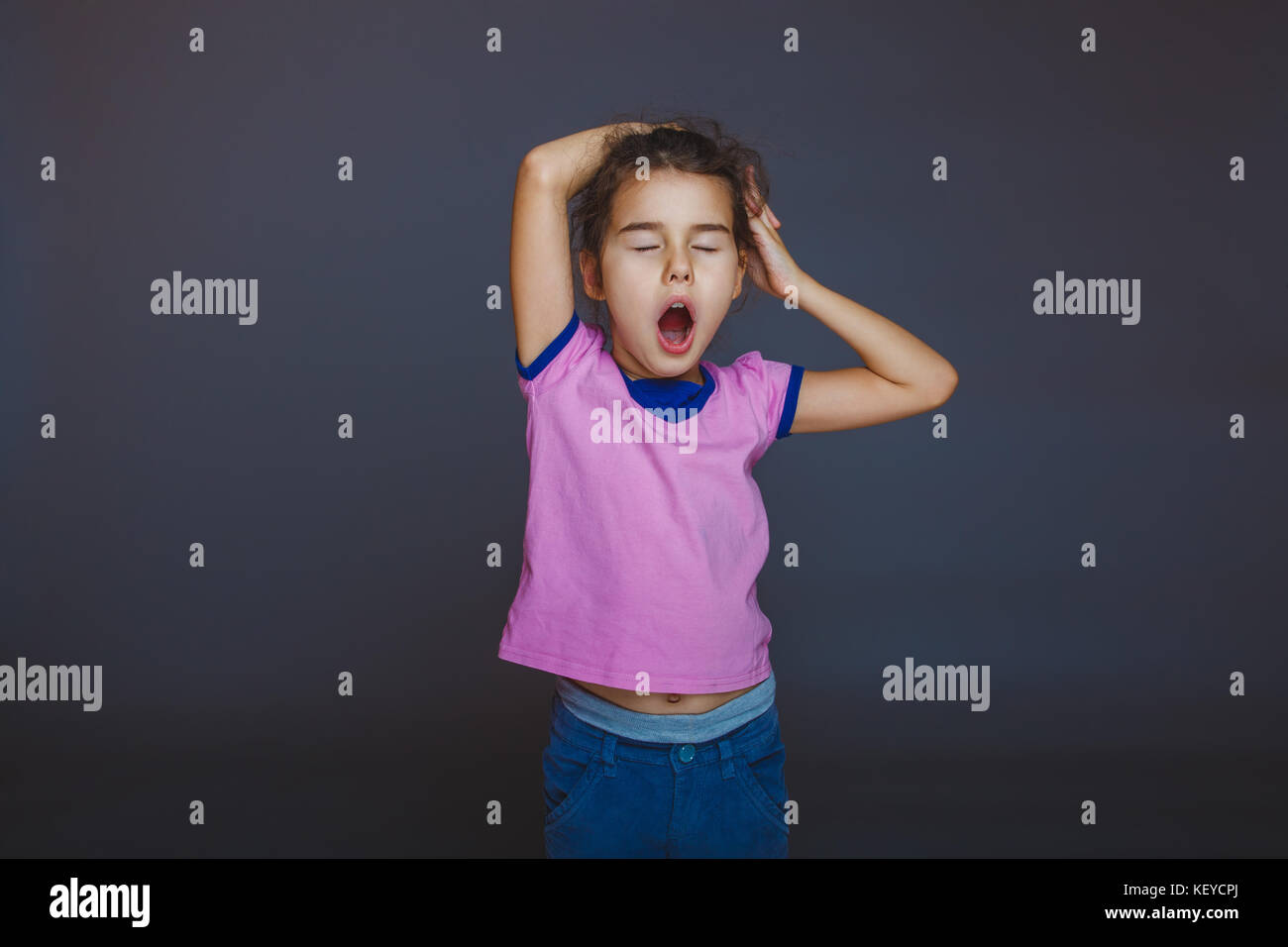 girl yawns wants to sleep on a gray background Stock Photo