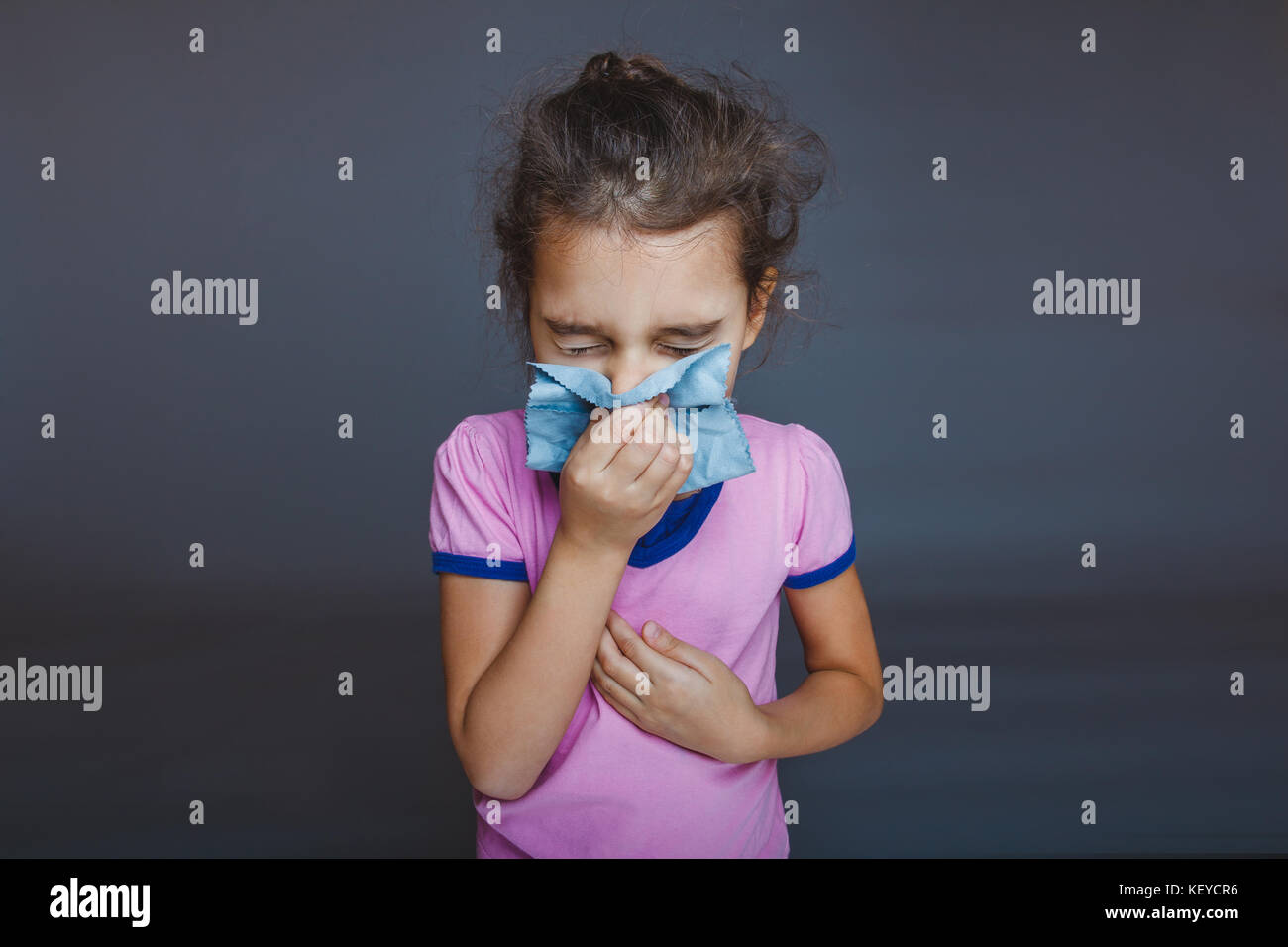 girl blowing his nose into a handkerchief on a gray background Stock Photo