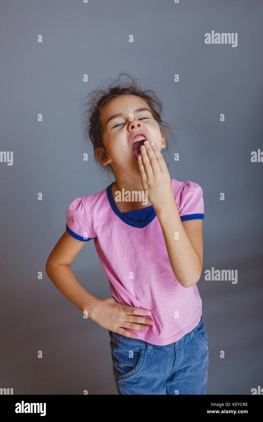 girl put her hand over her mouth yawns Stock Photo