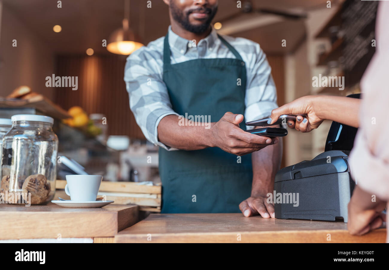 Customer using nfc technology to pay for her cafe purchase Stock Photo