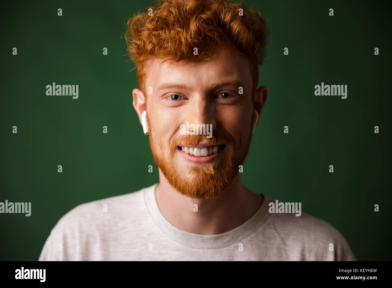 Close-up portrait of smiling curly redhead man, listening to music in  airpods, over green background Stock Photo - Alamy