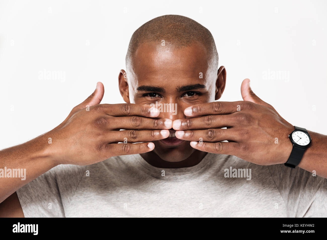 Happy african man covering his mouth and looking at the camera over ...