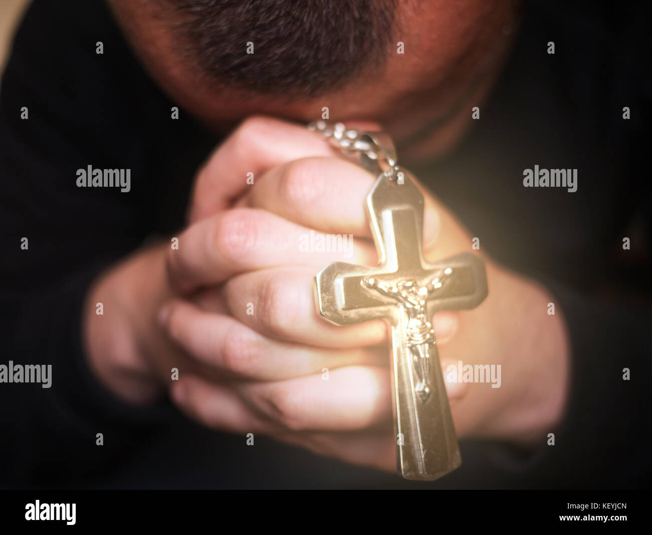 Man praying and holding a cross with Jesus, Christian concept Stock Photo