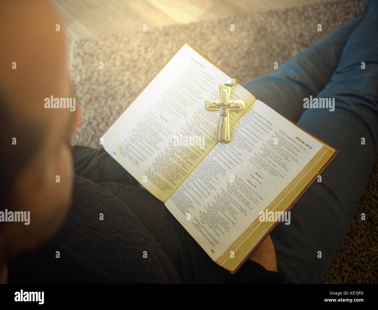 Man reading bible with a cross on it Stock Photo