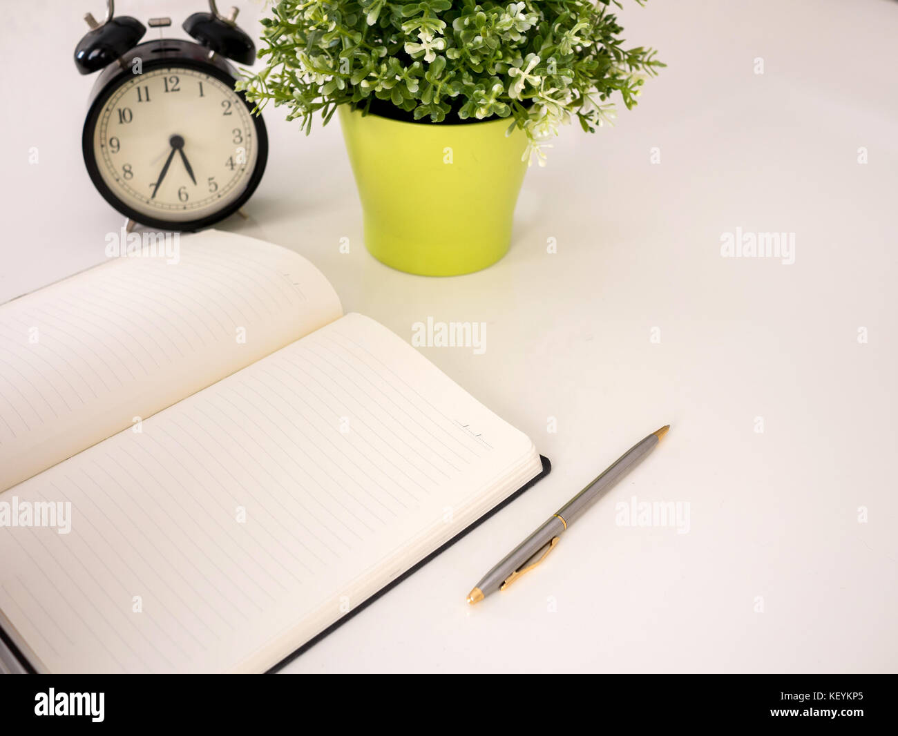Plain notebook with a pen and clock on white table Stock Photo - Alamy