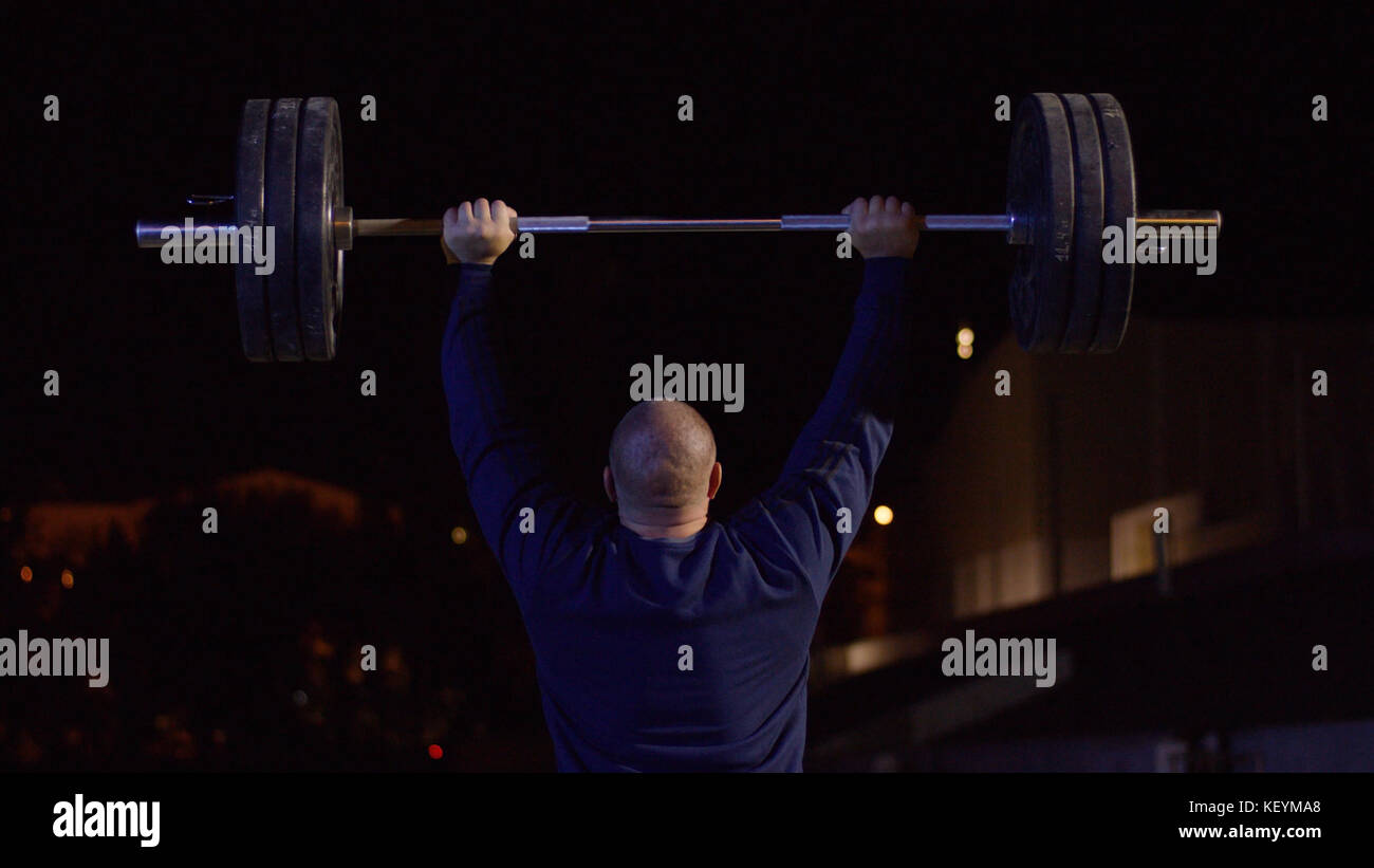 Weightlifter lifts the bar above his head. Strength training with a
