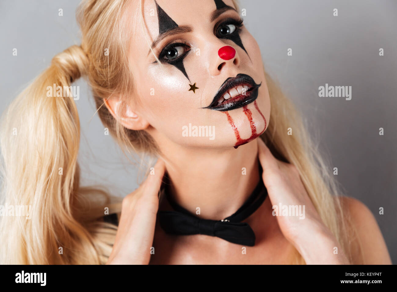 Close up image of young blonde woman in halloween make up looking at the camera over gray background Stock Photo