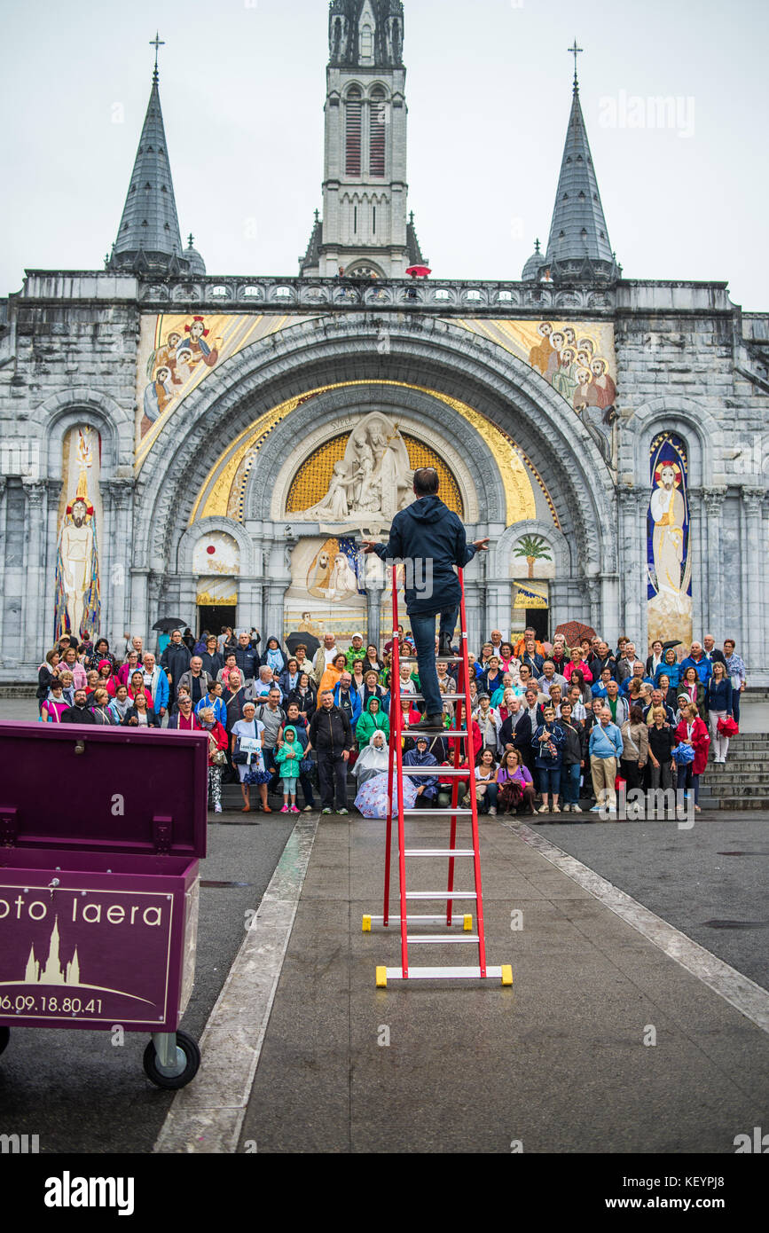 photographer taking pictures of group photo of tourists in front of the cathedral in Lourdes, France, Europe. Stock Photo