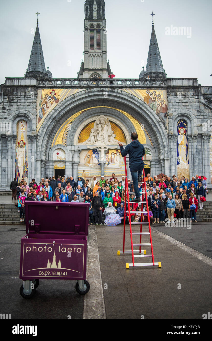 photographer taking pictures of group photo of tourists in front of the cathedral in Lourdes, France, Europe. Stock Photo