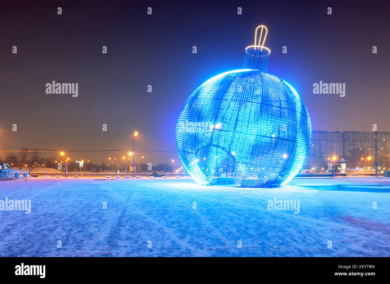 Giant glowing blue Christmas ball on the street with snow Stock Photo