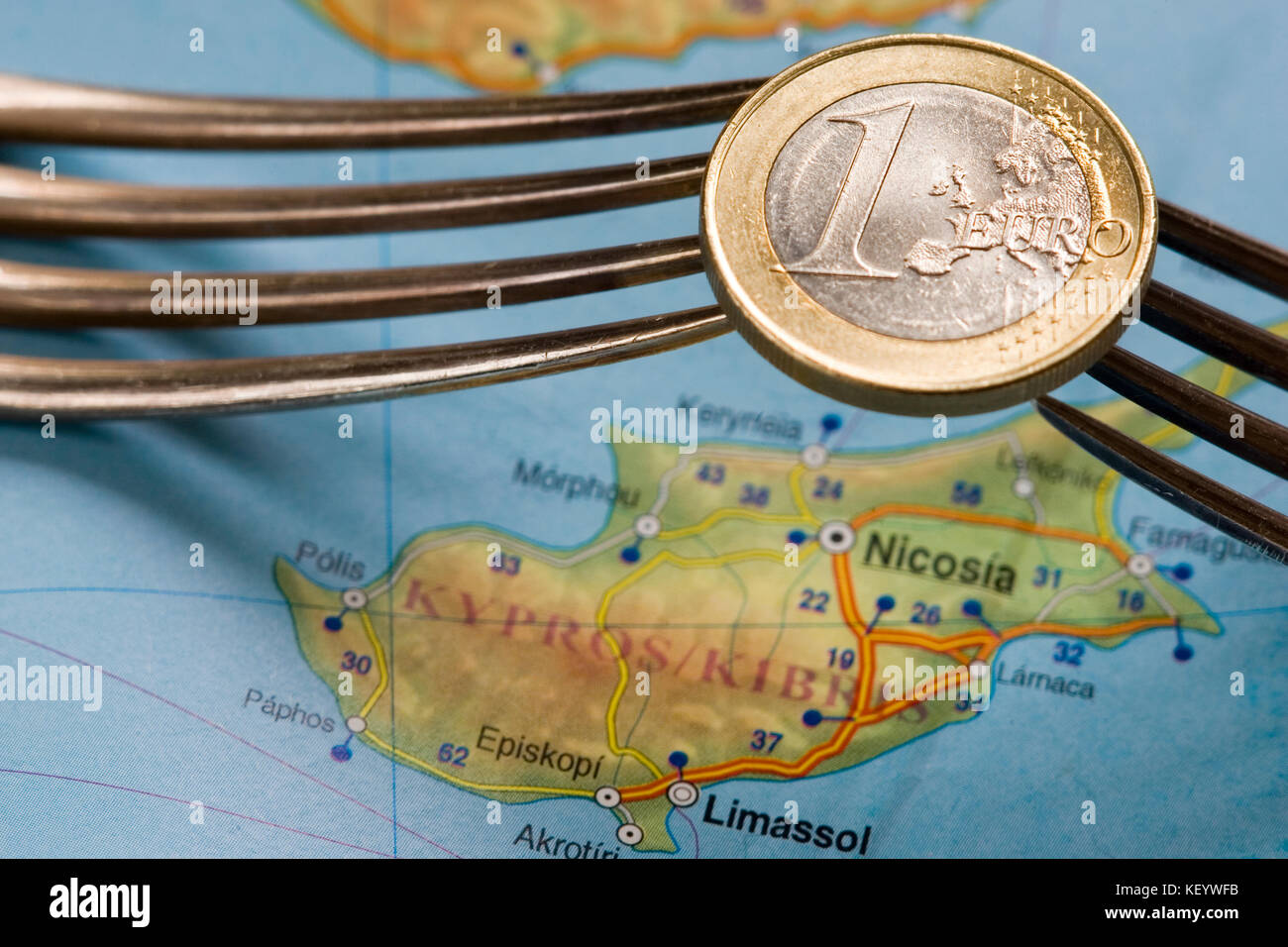 Two forks hold one euro coin over Cyprus map. Stock Photo