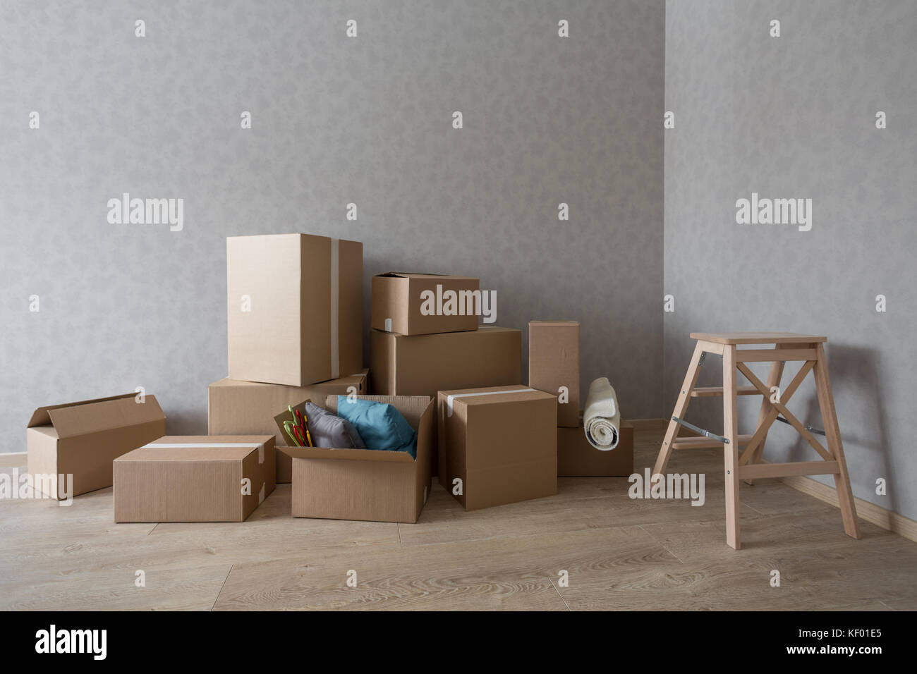 Cardboard boxes pile in new empty room with step-ladder Stock Photo