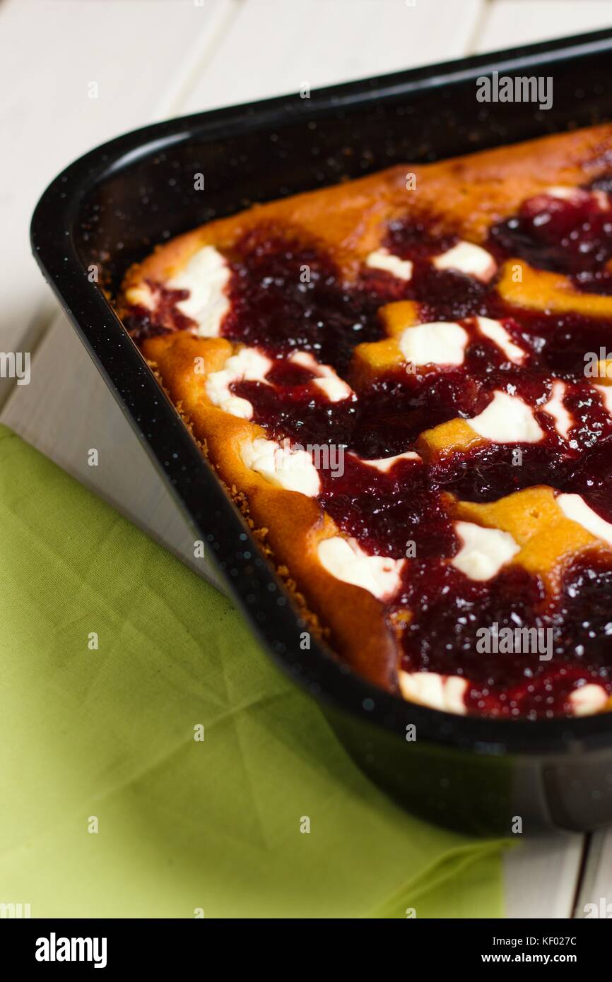 Fresh baked cake with cottage cheese and fruit jam in black baking tray
