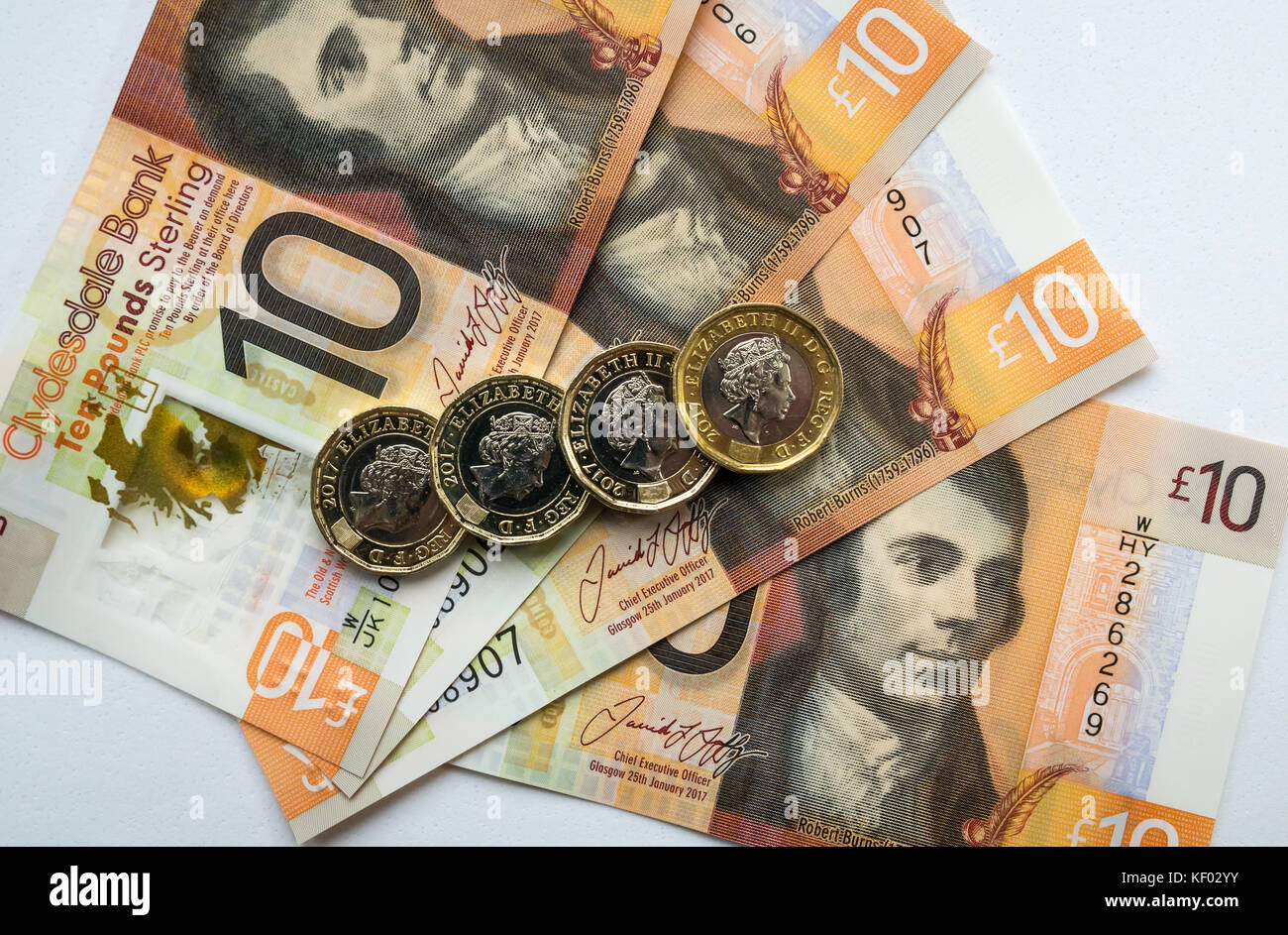 Plastic polymer Clydesdale Bank Scottish ten pounds £10 banknotes with Robert Burns and hexagonal one pound £1 coins on a plain white background Stock Photo