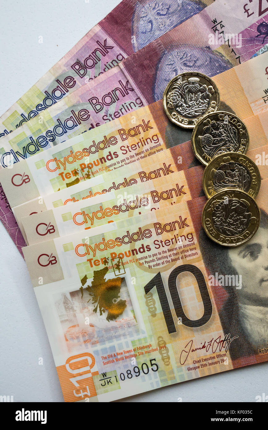 Clydesdale Bank Scottish twenty £20, plastic polymer ten £10 banknotes with Robert Burns and hexagonal one pound £1 coins on plain white background Stock Photo