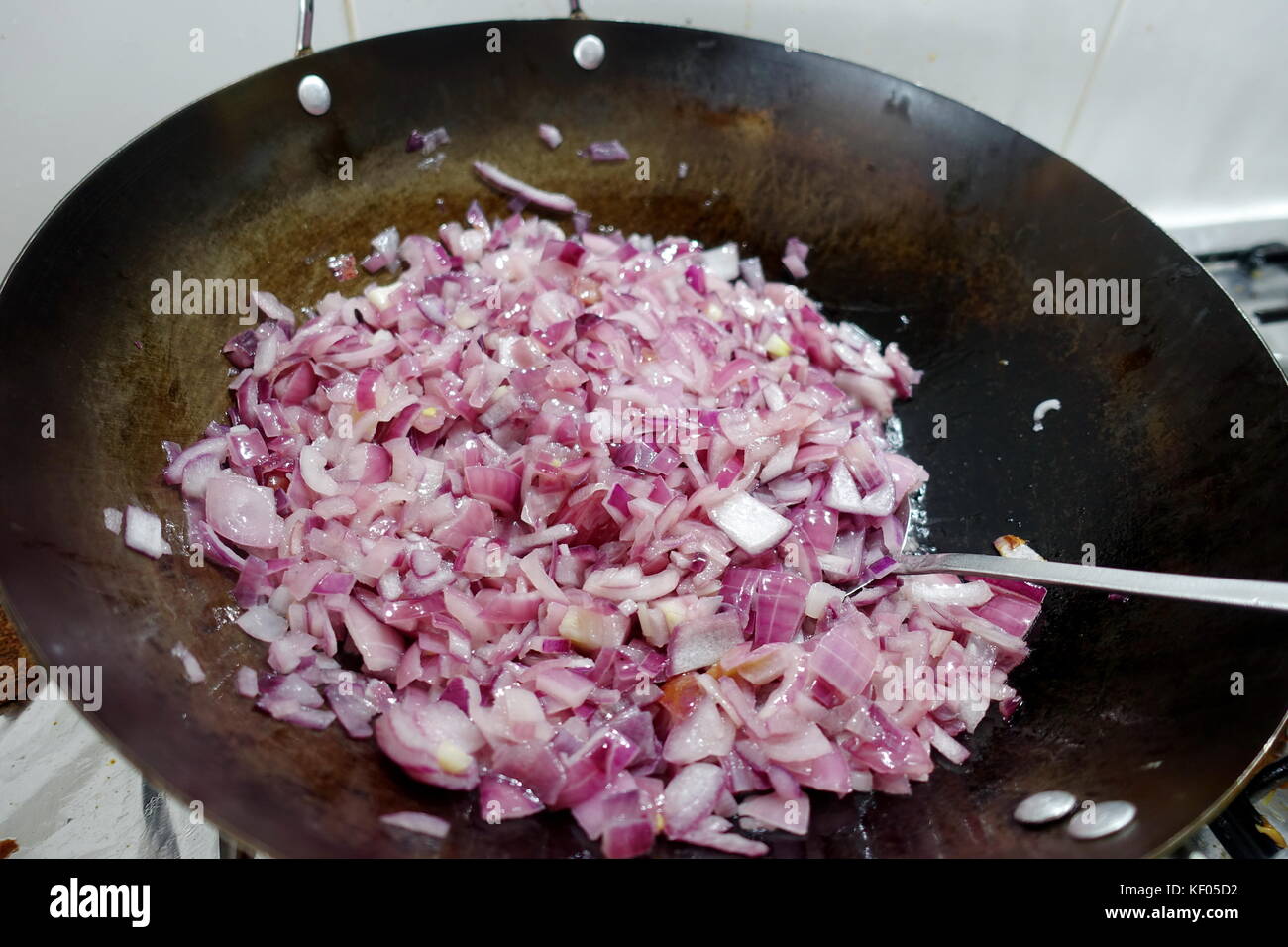 Frying red onions in carbon steel wok Stock Photo