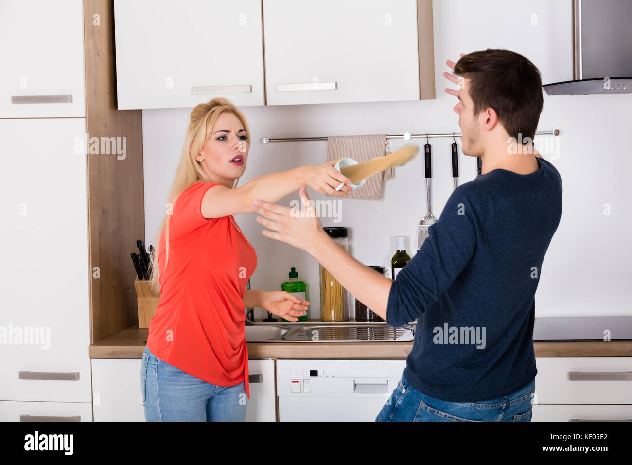 Angry Woman Throwing Cup Of Coffee On Husband While Quarrel About Infidelity And Divorce Stock Photo