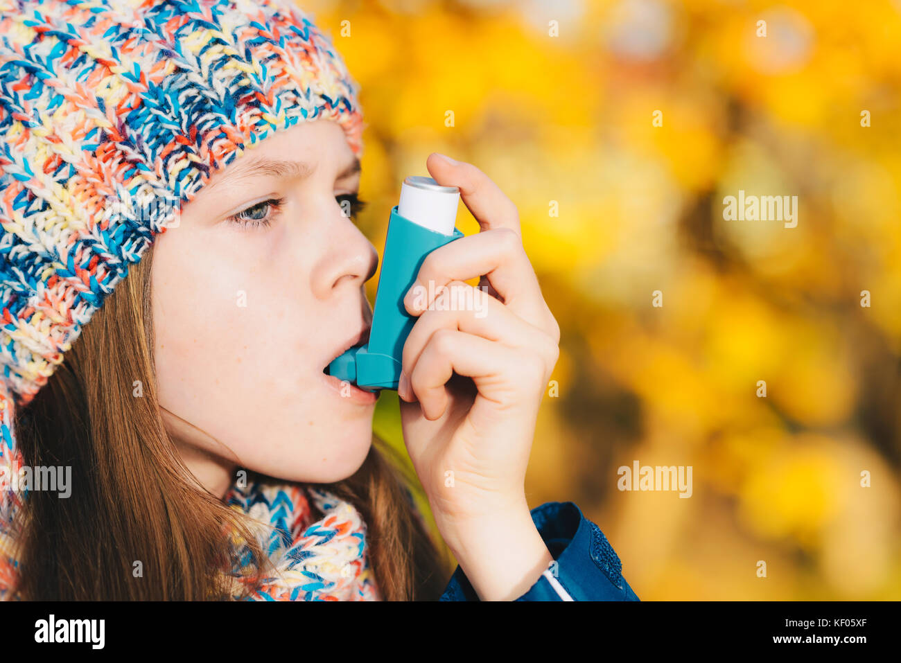 Asthma patient girl inhaling medication for treating shortness of breath and wheezing in a park. Chronic disease control, allergy induced asthma remed Stock Photo