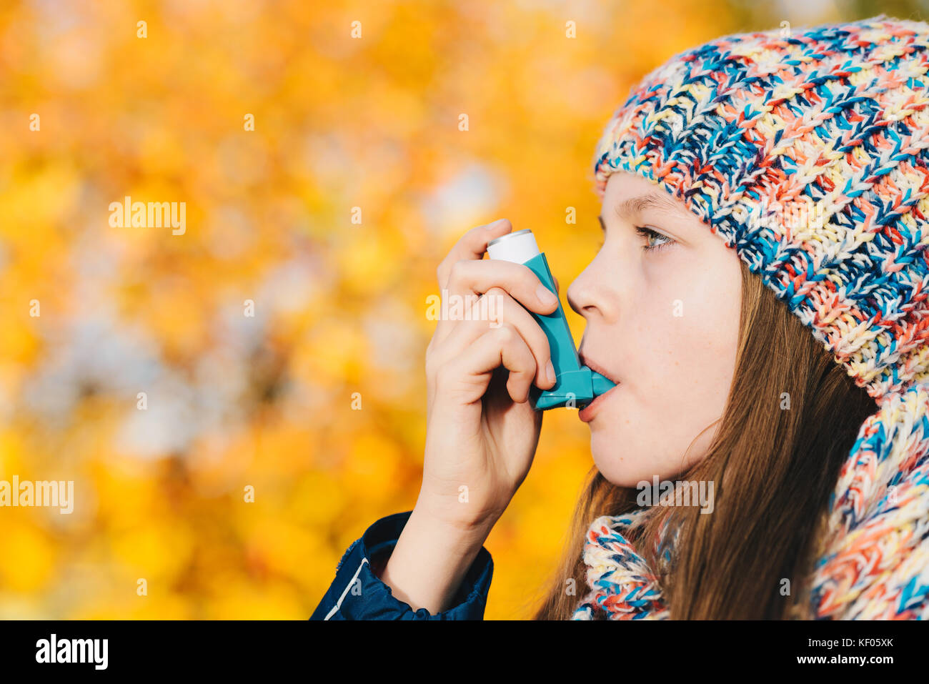 Asthma patient girl inhaling medication for treating shortness of breath and wheezing in a park. Chronic disease control, allergy induced asthma remed Stock Photo