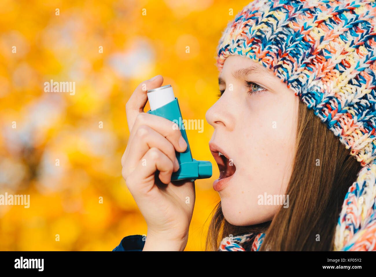 Young girl using asthma inhaler in a park chronic disease control