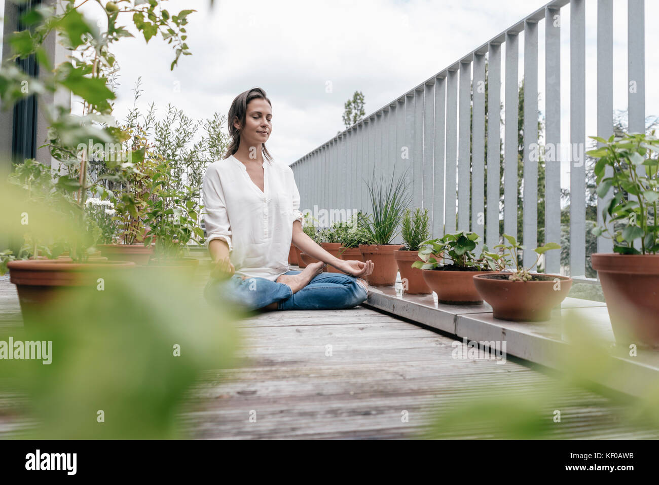 Woman sitting on balcony practicing yoga Stock Photo