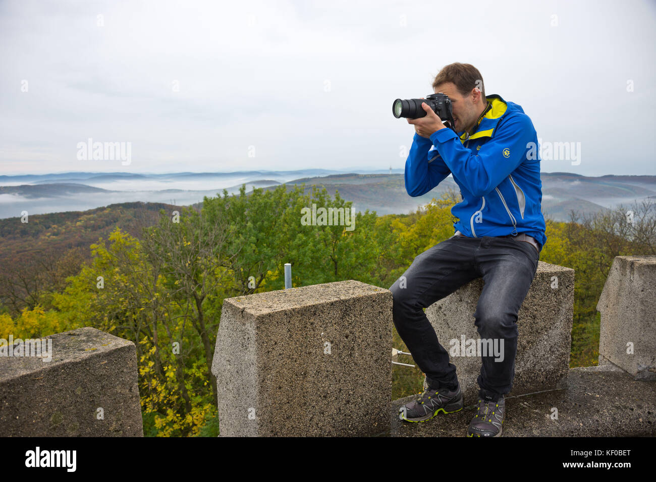 Photographer taking a photo on a mountain in Wienerwald on a misty and gloomy autumn day. Stock Photo