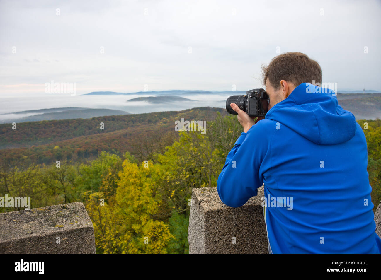 Photographer taking a photo on a mountain in Wienerwald on a misty and gloomy autumn day. Stock Photo