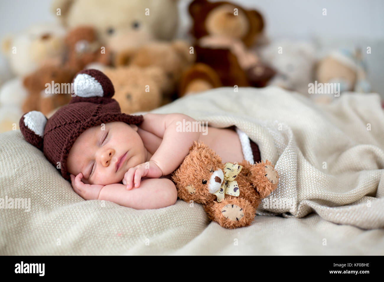Little newborn baby boy, sleeping with teddy bear at home in bed
