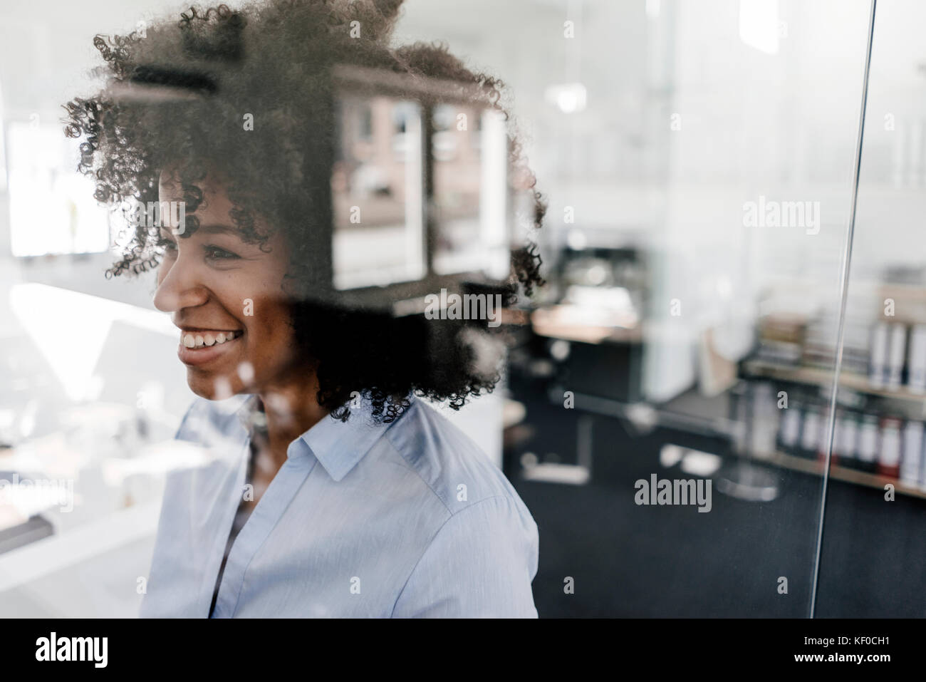 Smiling young woman behind glass wall in office Stock Photo Alamy