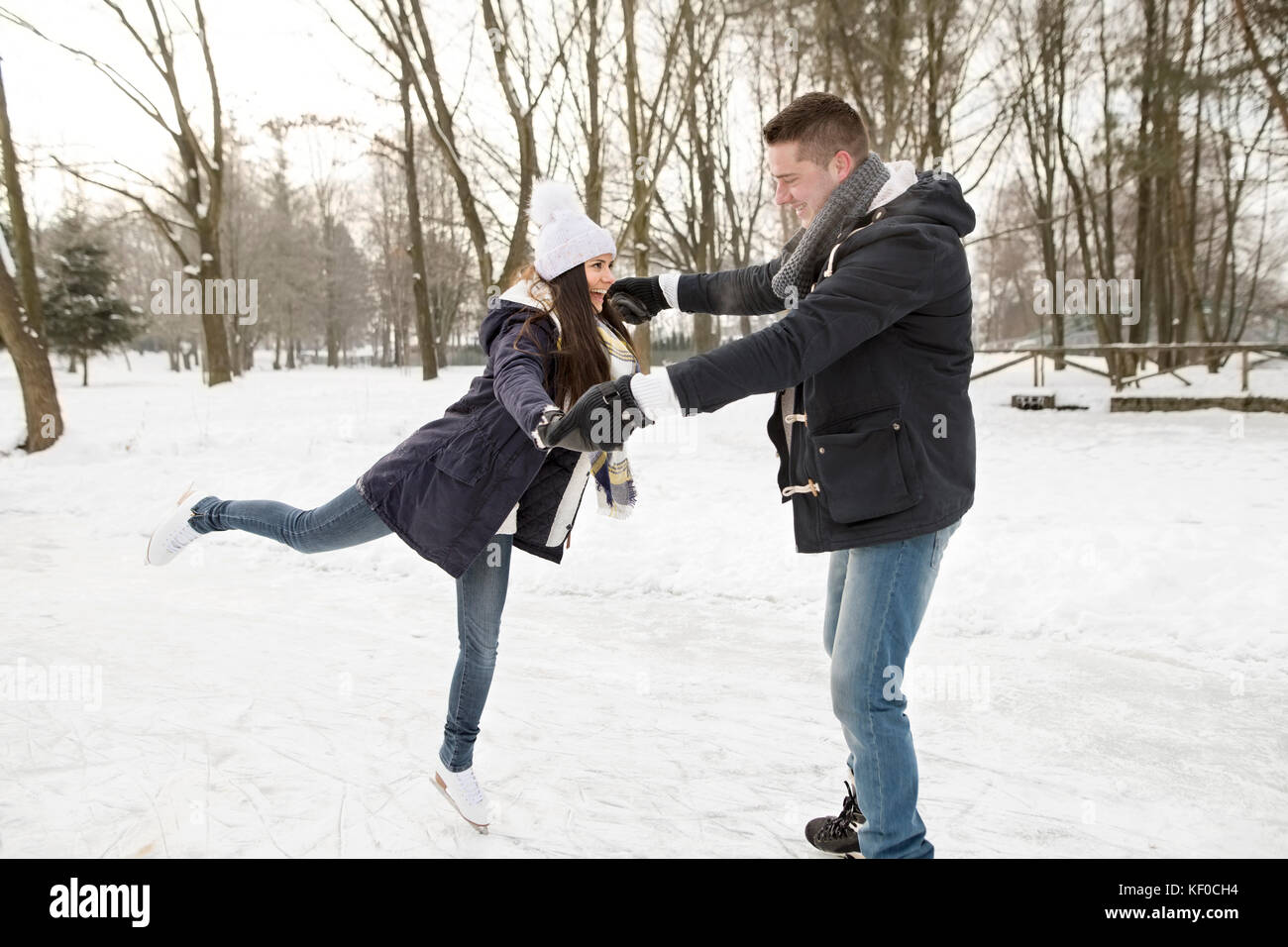 Couple ice skating on a frozen lake, woman balancing on one leg Stock ...