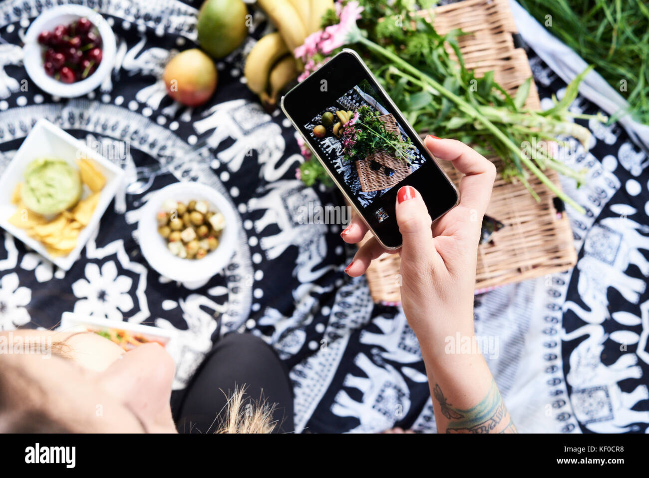 Uk, London, Hampstead Heath Park, overhead unrecognizable girl taking picture of food on picnic blanket, friends picnic at the park Stock Photo