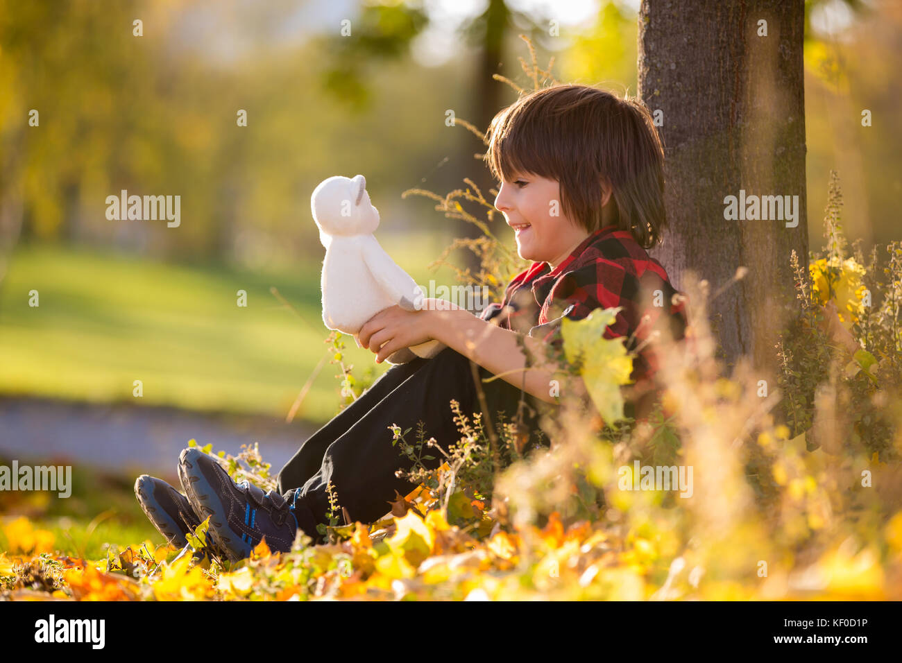Adorable little boy with teddy bear in the park on an autumn day in the ...