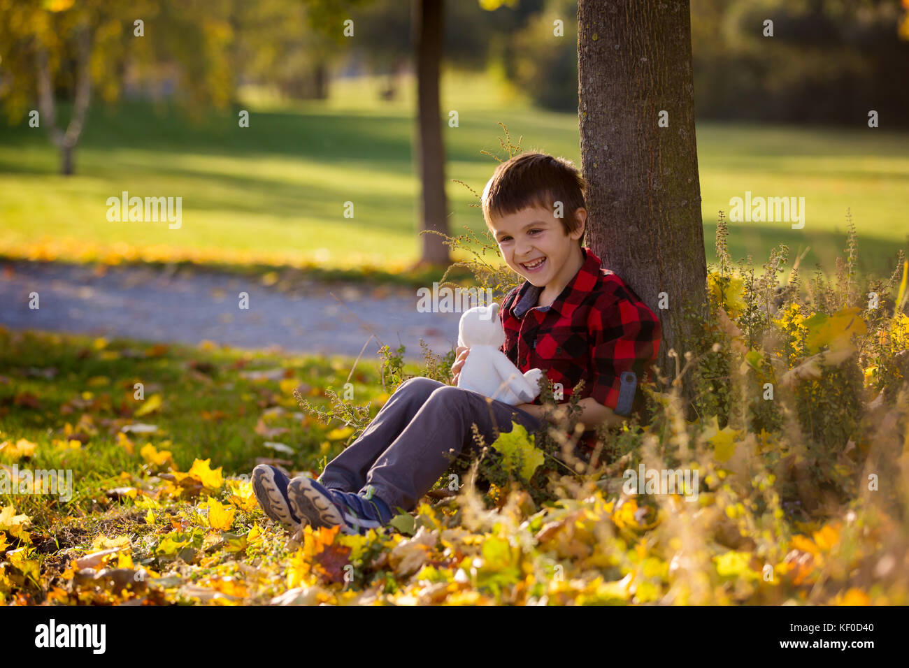 Adorable little boy with teddy bear in the park on an autumn day in the ...