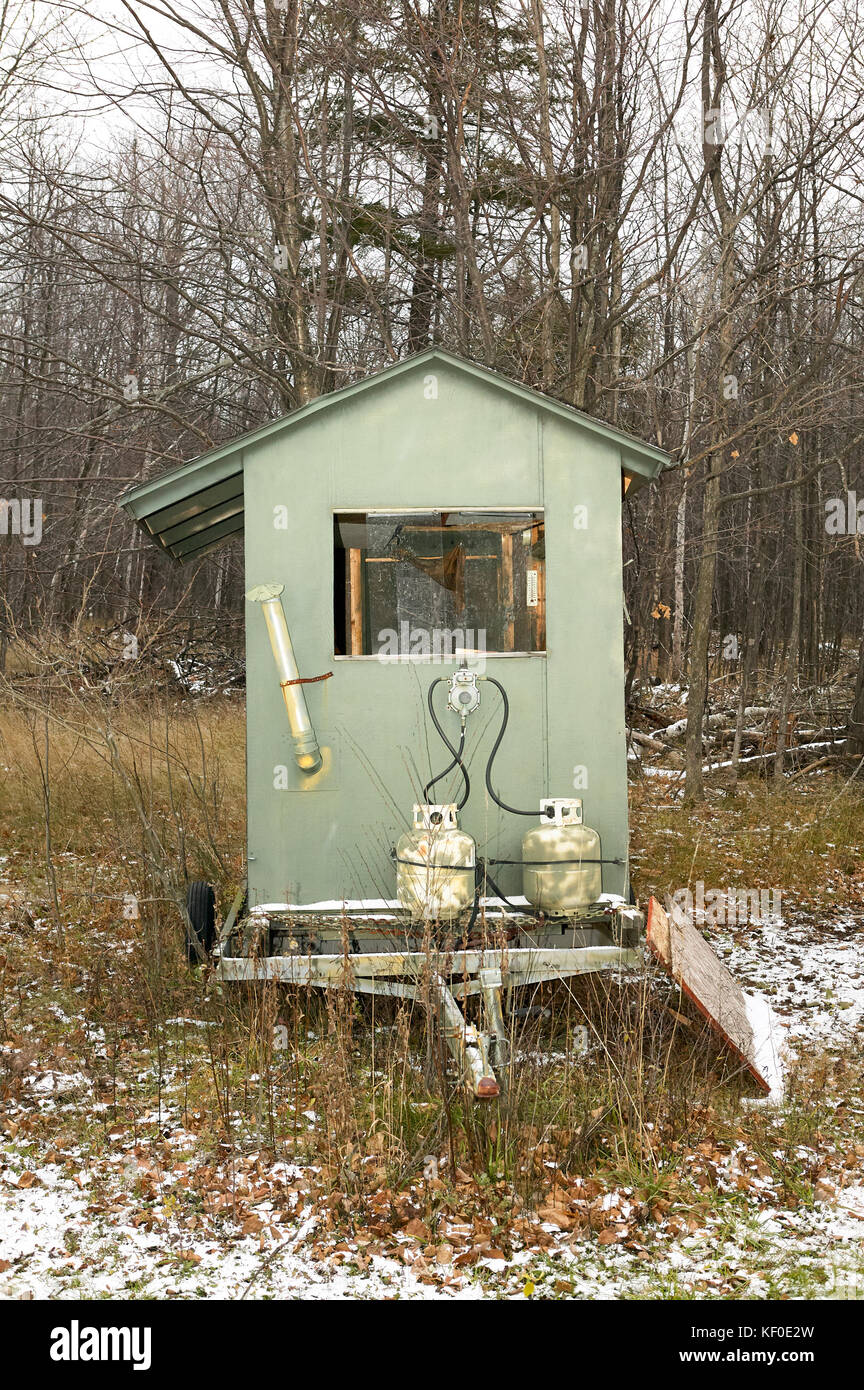 Small deer blind fitted with gas bottles on a trailer in snowy woodland with leafless deciduous trees to conceal hunters during the deer hunt Stock Photo