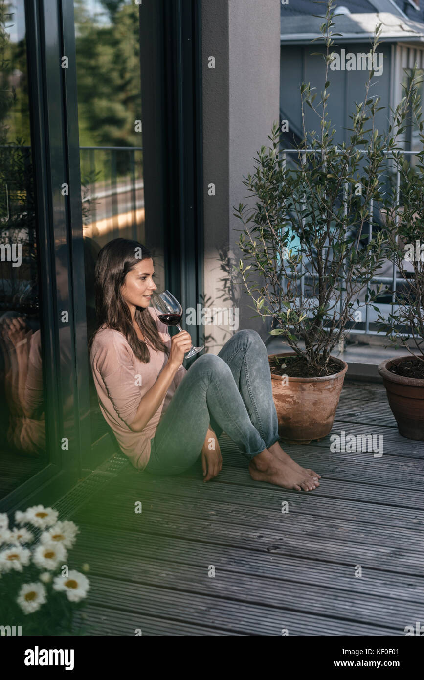 Woman with glass of red wine relaxing on balcony Stock Photo - Alamy