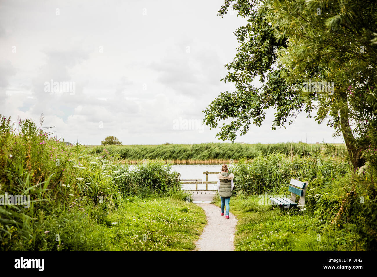 Girl walking on path towards lake Stock Photo