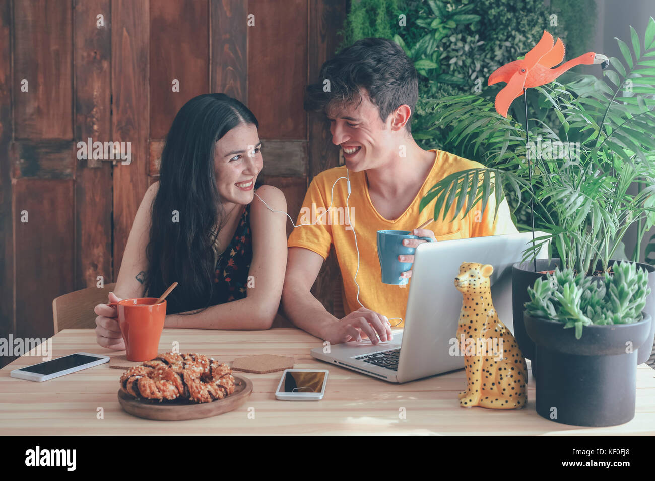 Young couple having coffee and chocolate braids using laptop at home Stock Photo