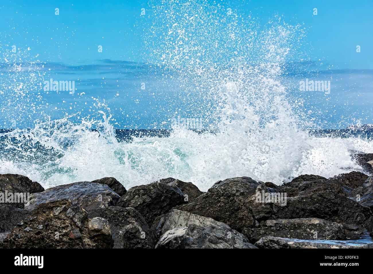 The tidal wave is broken into small splashes about the coastal stones Stock Photo