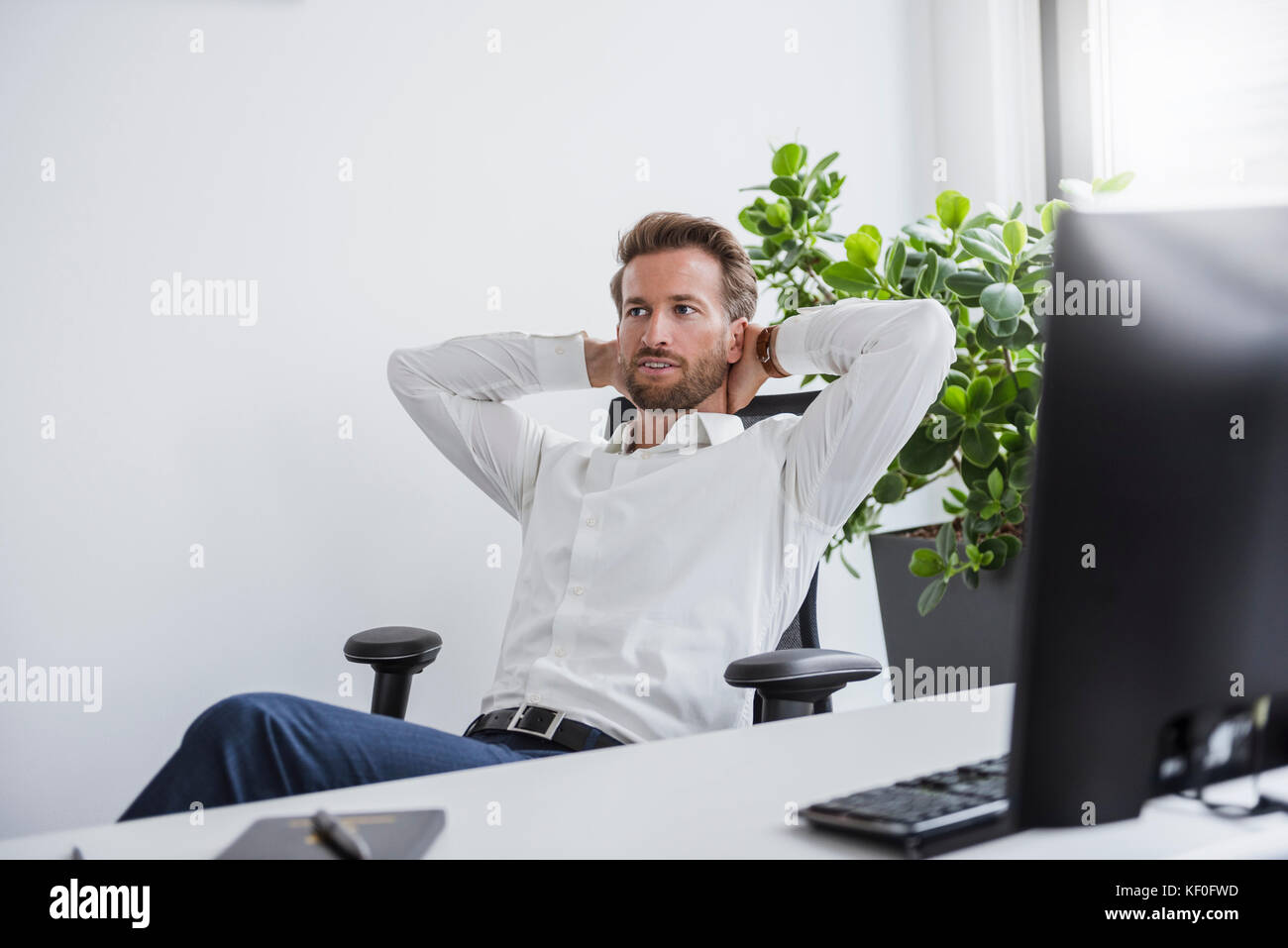 Portrait of businessman relaxing at desk in his office Stock Photo